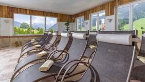 Un'area benessere con poltrone relax, vista sulle montagne e rivestimenti in legno.