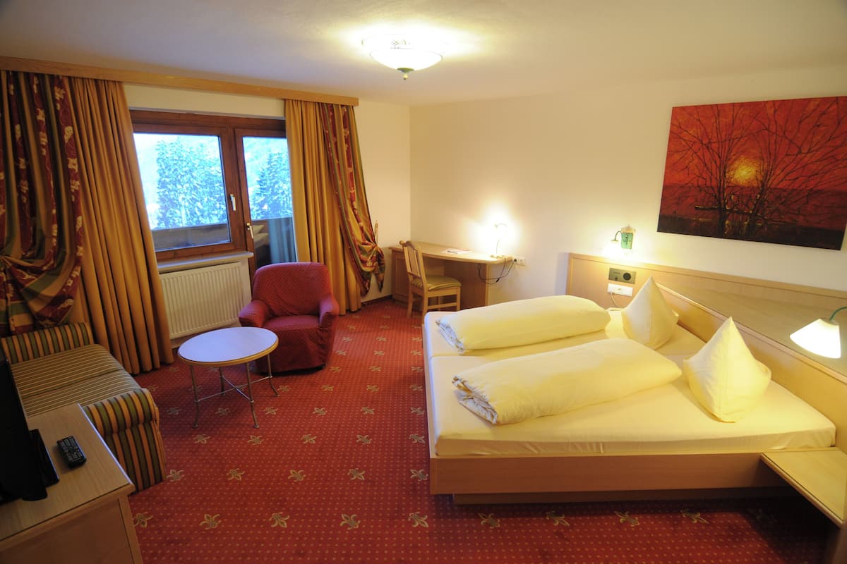 Ein Hotelzimmer mit Bett, Schreibtisch, Stuhl und einem kleinen Tisch.