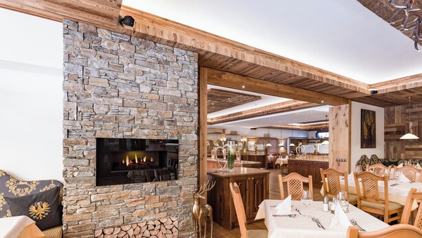 Un ristorante con camino in pietra, soffitto in legno e sala da pranzo con tavoli e sedie.