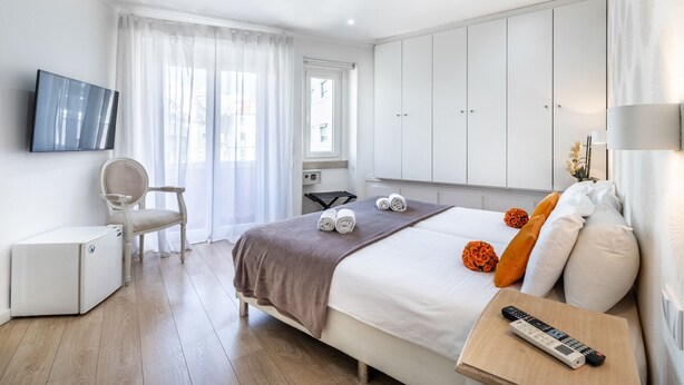 Una habitación de hotel con cama, escritorio, silla, televisor y armario.