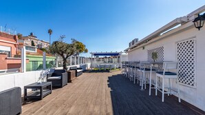 Terraza en la azotea con mobiliario exterior, una pérgola y vistas de la ciudad.