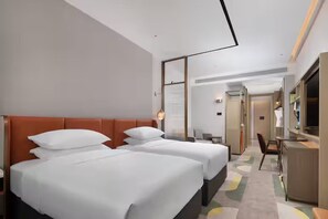 Habitación de hotel con dos camas, un escritorio y un espejo.