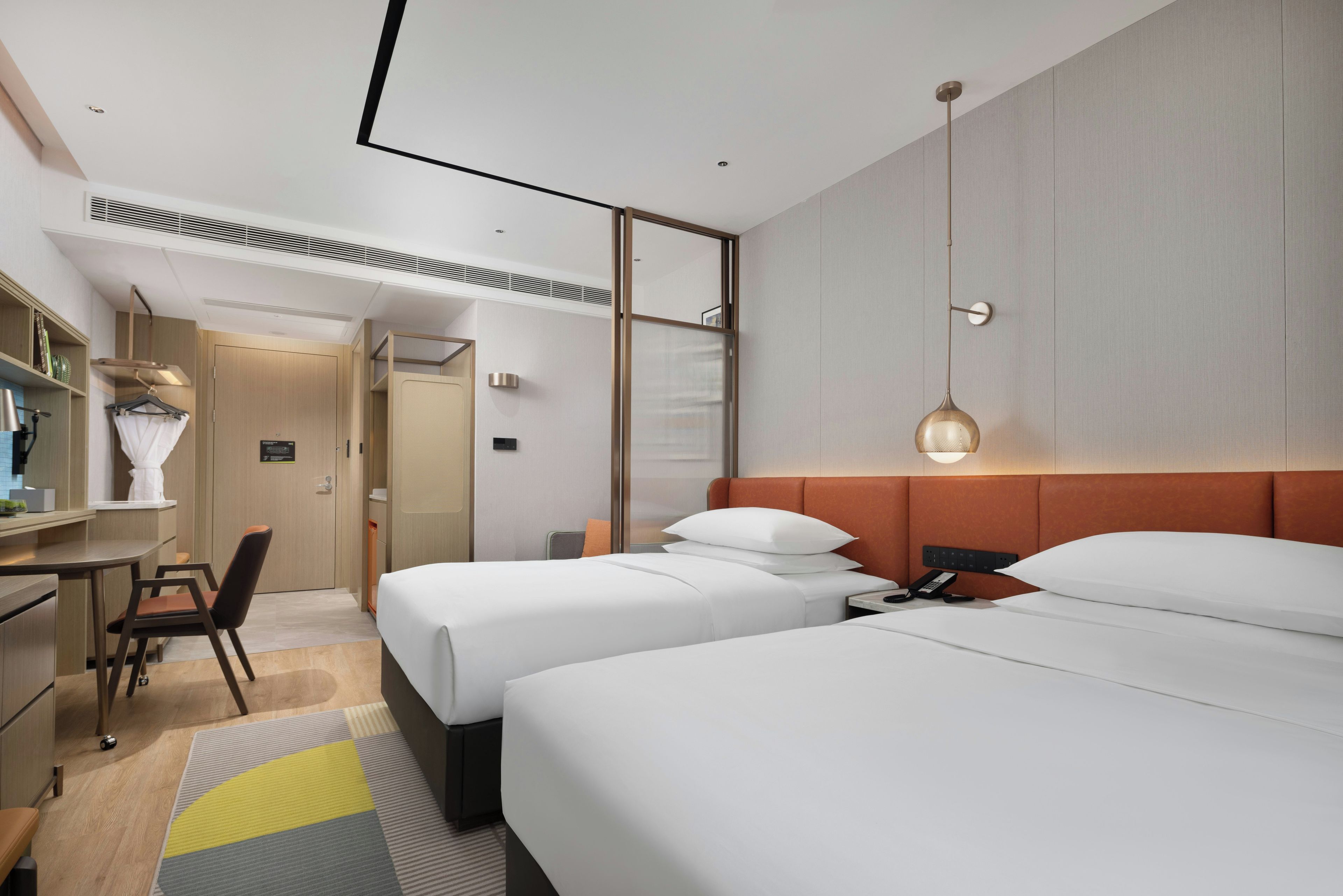Une chambre d’hôtel moderne avec deux lits, un bureau et une chaise.