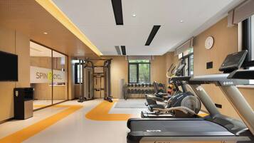 A gym with treadmills, weights, and a wall-mounted clock.