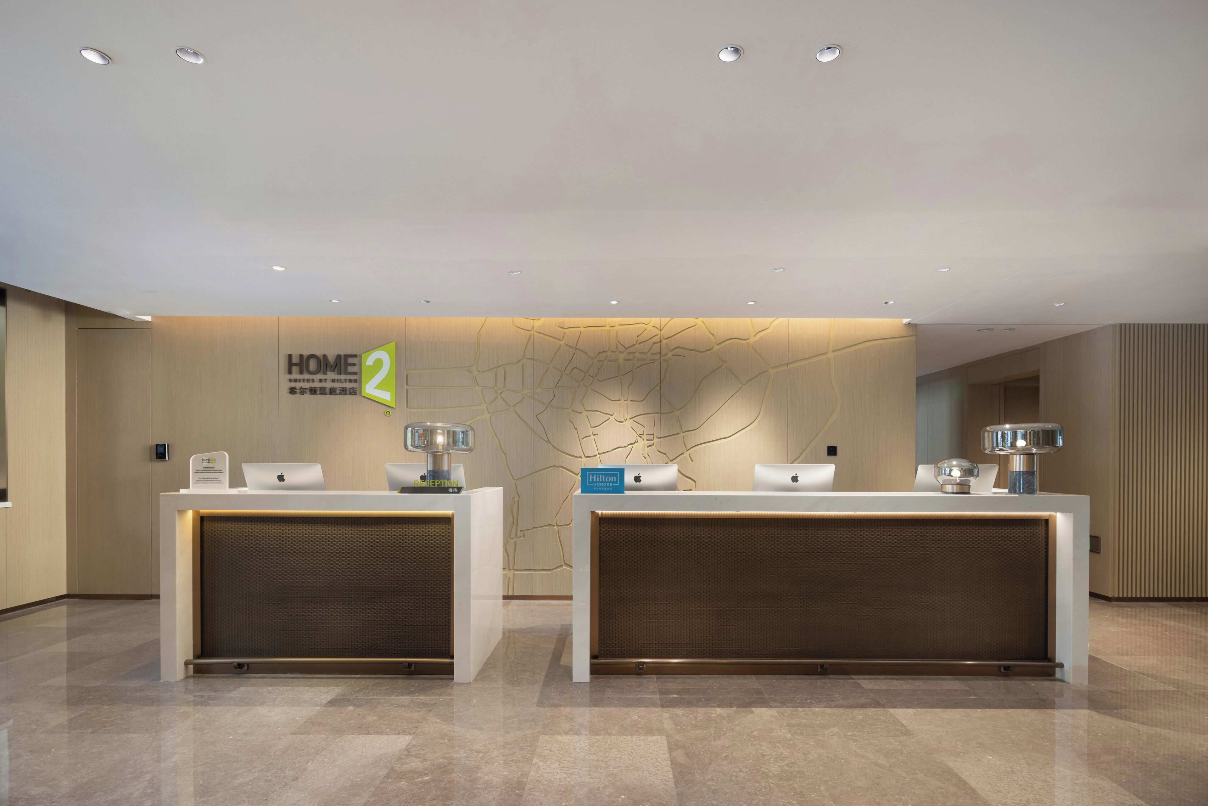 A hotel reception desk with two counters, a reception sign, and a wall with a map design.