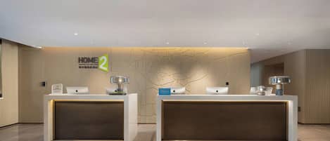 A hotel reception desk with two counters, a reception sign, and a wall with a map design.