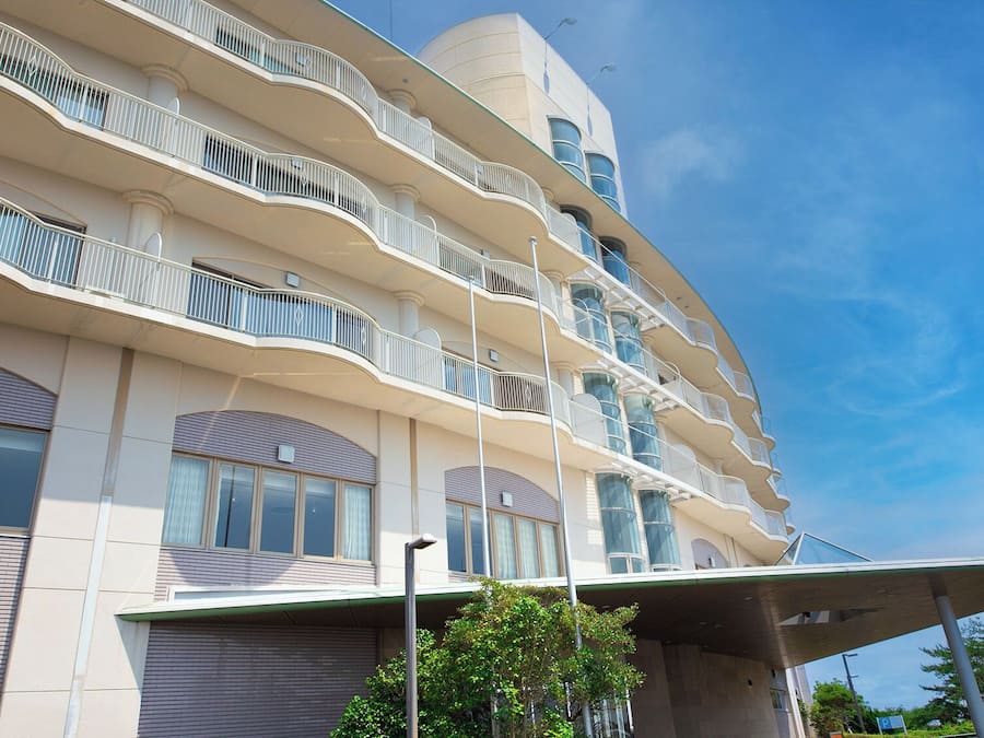 A multi-story building with balconies, large windows, and a curved architectural design.
