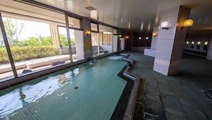 Une piscine à l’eau claire, entourée de murs et de fenêtres recouverts de carreaux.