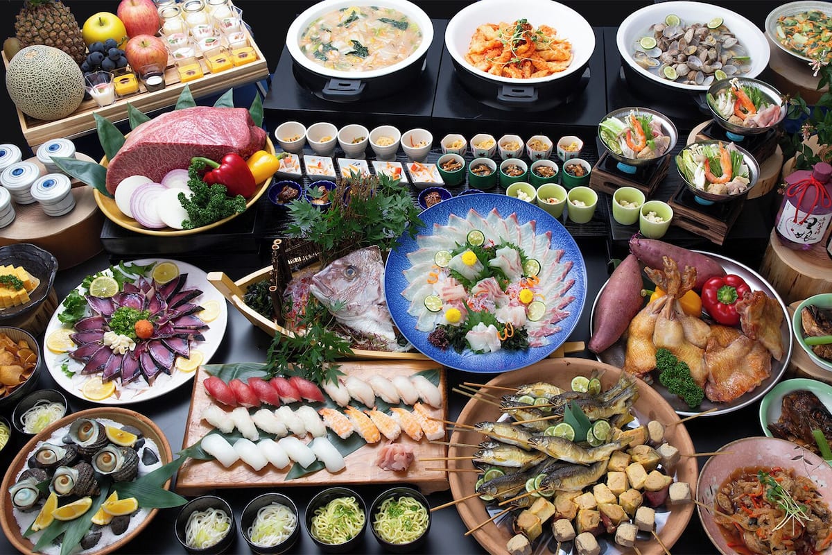 Een verscheidenheid aan gerechten en etenswaren, waaronder sushi, sashimi en zeevruchten, gerangschikt op een tafel.