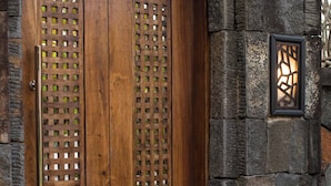 A wooden door with a lattice design, set in a stone wall.