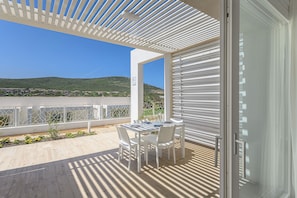 Een balkon met een tafel en stoelen, uitzicht op een groen landschap en een witte balustrade.