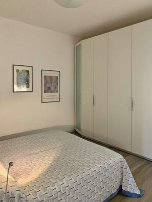 Un dormitorio con una cama, un armario y dos cuadros en la pared.