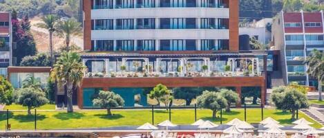 Un hotel moderno con varios pisos, una zona de piscina y vistas a la playa.