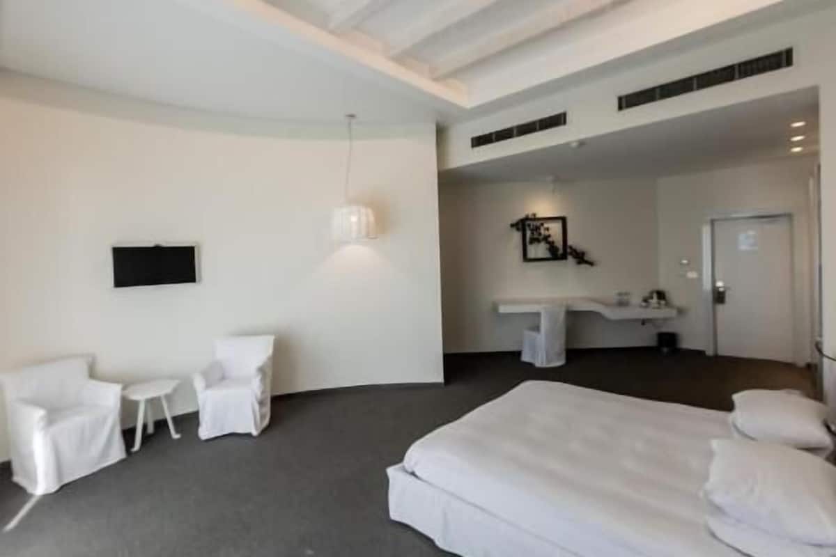Habitació d'hotel moderna amb un llit gran, un escriptori, una cadira i una taula petita.