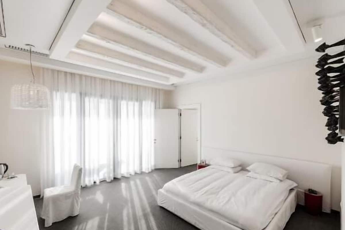 Habitació d'hotel moderna amb un llit gran, una taula de treball i una cadira.