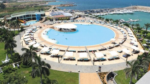 A resort with a large circular pool, beachside lounge areas, and a marina. - Miramar Hotel Resort & Spa (Qalamoun)