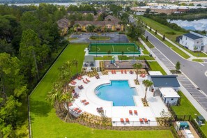 A swimming pool with sun loungers, a tennis court, and a parking area. - South Facing Pool! Private Game Room+Near Disney (Kissimmee)