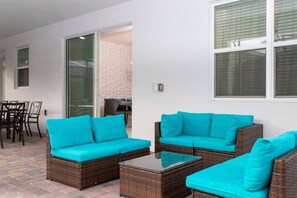 An outdoor patio area with wicker furniture and turquoise cushions. - South Facing Pool! Private Game Room+Near Disney (Kissimmee)