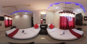 A hotel room with two beds, red curtains, a ceiling fan, and a flat-screen TV. - Hotel Briteway  (Mumbai)