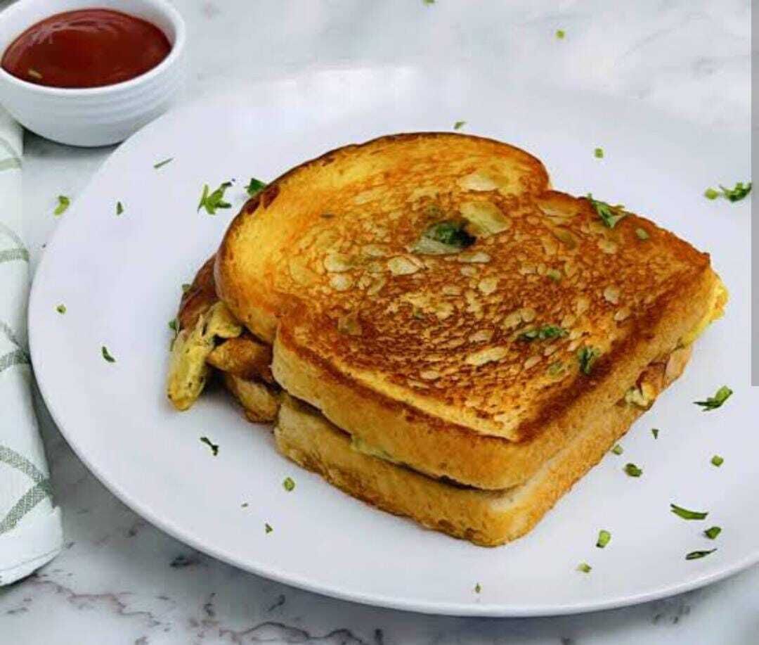 A grilled sandwich on a white plate with a side of ketchup.