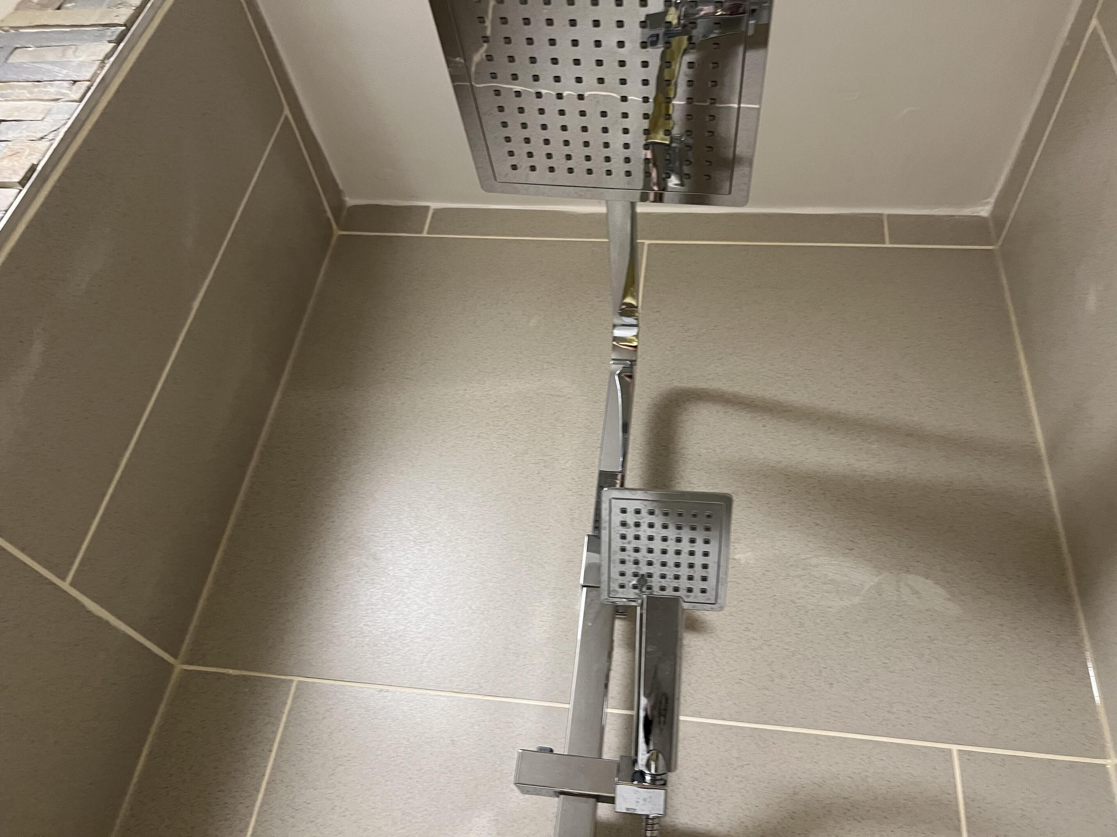 A shower with a control panel and a handheld showerhead.