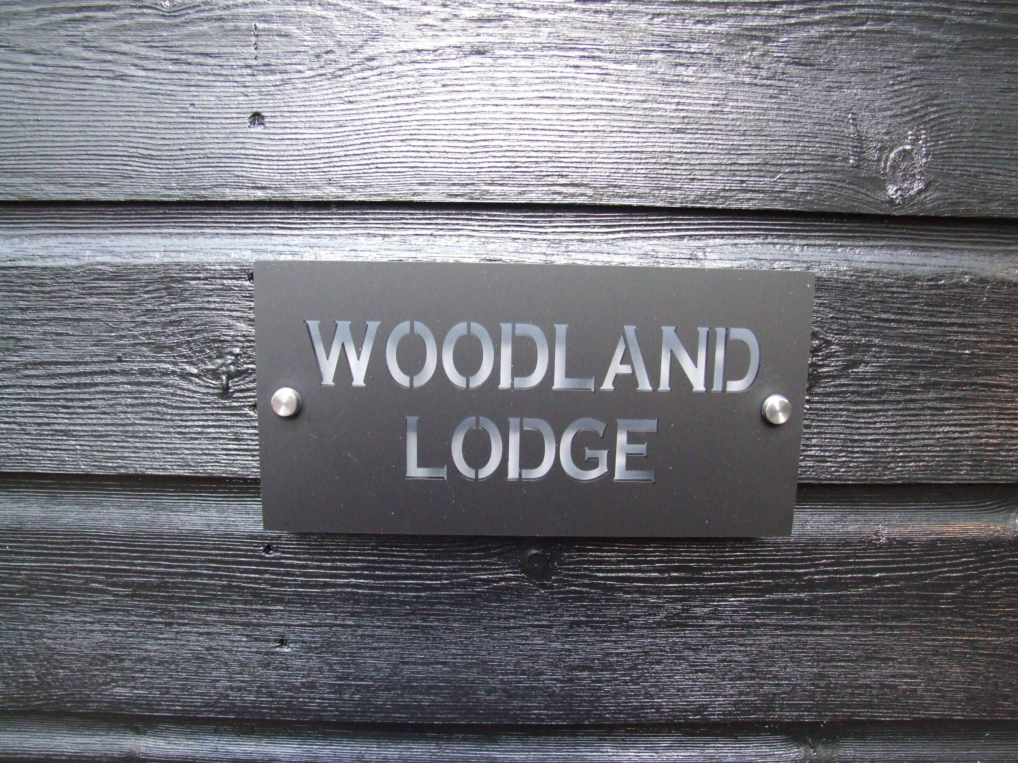 A sign on a wooden wall that reads "WOODLAND LODGE".