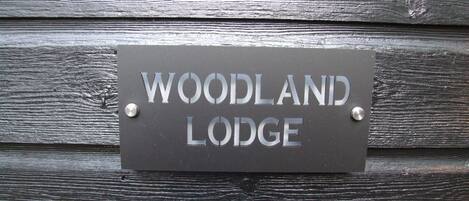 A sign on a wooden wall that reads "WOODLAND LODGE".