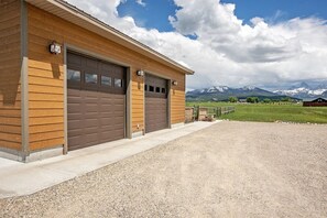 Un bâtiment doté de deux portes de garage, d’une allée gravillonnée et, en arrière-plan, d’un paysage montagneux.