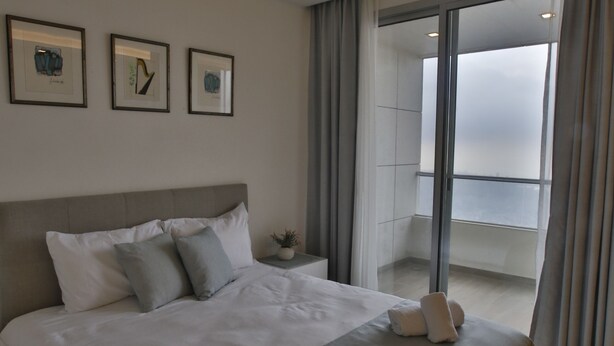 Een hotelkamer met een groot bed, een nachtkastje en uitzicht op een balkon.