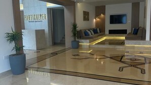 Een moderne lobby met een glazen salontafel, een bank en een flatscreen-televisie.