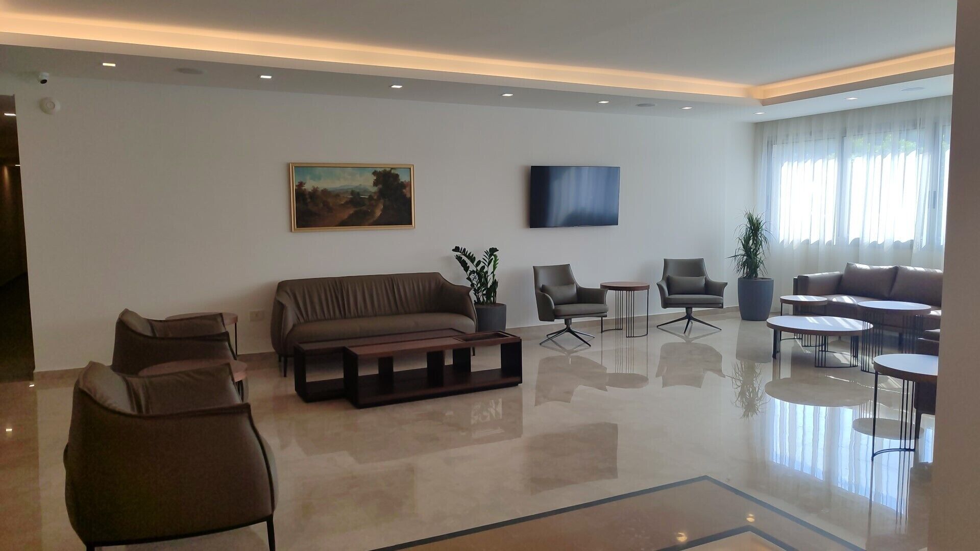 A modern living room with a sofa, armchairs, a coffee table, and a TV.