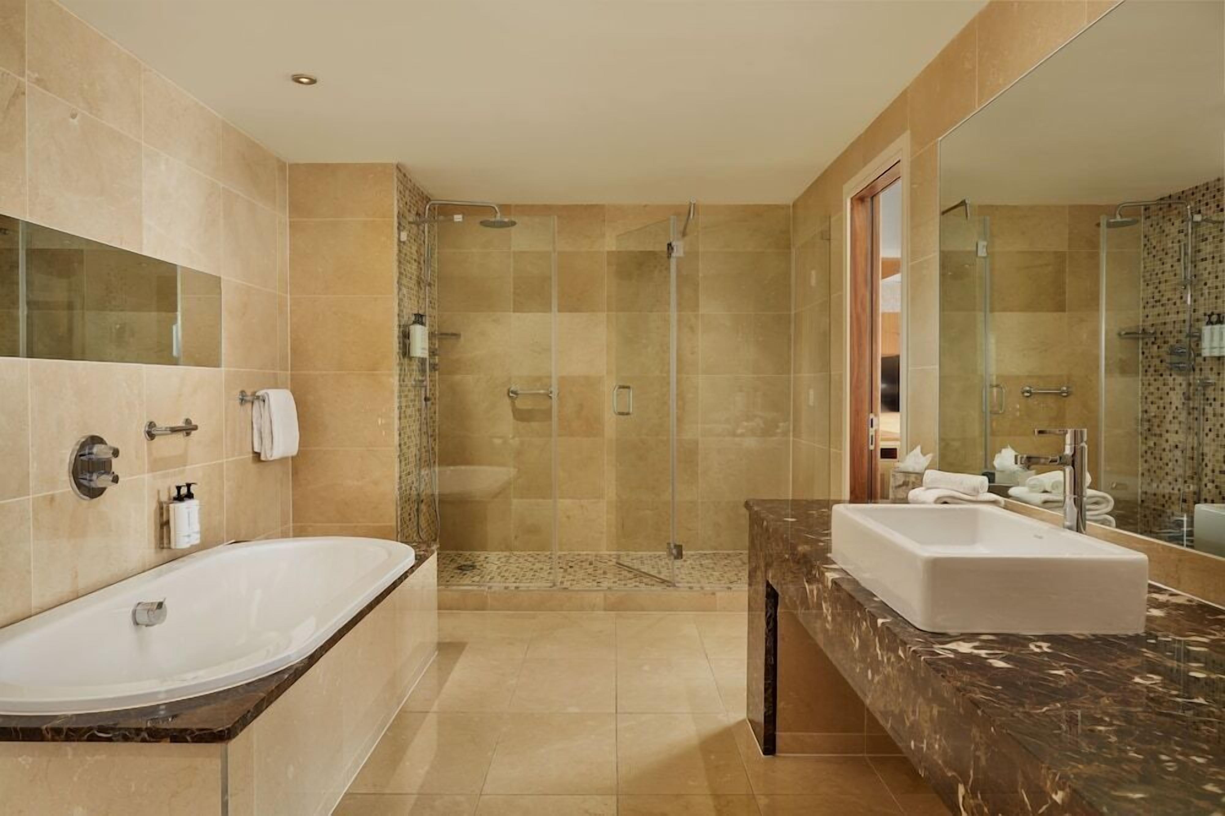 A modern bathroom with a large bathtub, a separate shower area, and a marble countertop with a sink.