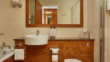 A bathroom with a wooden vanity, a sink, a mirror, a toilet, and a shower.