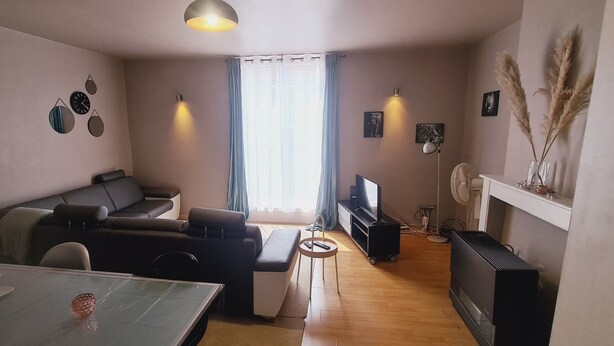 A living room with a sofa, TV, and a dining area with a table. - Duplex Close to the Casino de Namur (Namur)