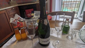 A bottle of Ferrari Brut wine, two glasses, and snacks on a table in a kitchen with a view of the sea. - Il Cavallino vacation home on Lake Ceresio and Lugano (Lombardia)