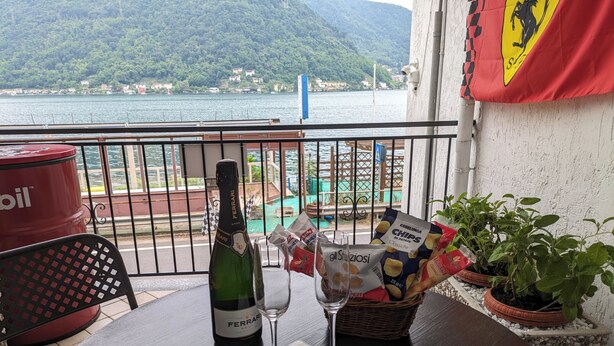 A balcony with a bottle of Ferrari Brut champagne, a glass, snacks, and potted plants. - Il Cavallino vacation home on Lake Ceresio and Lugano (Lombardia)