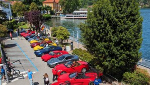 A parking area with multiple sports cars, a body of water, and a bridge in the background. - Il Cavallino vacation home on Lake Ceresio and Lugano (Lombardia)