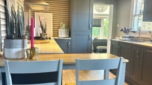 A modern kitchen with grey cabinets, a wooden dining table, and two white chairs. - Twickenham Green (Twickenham)