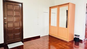 Una habitación con puerta de madera, un armario y un cubo de basura.