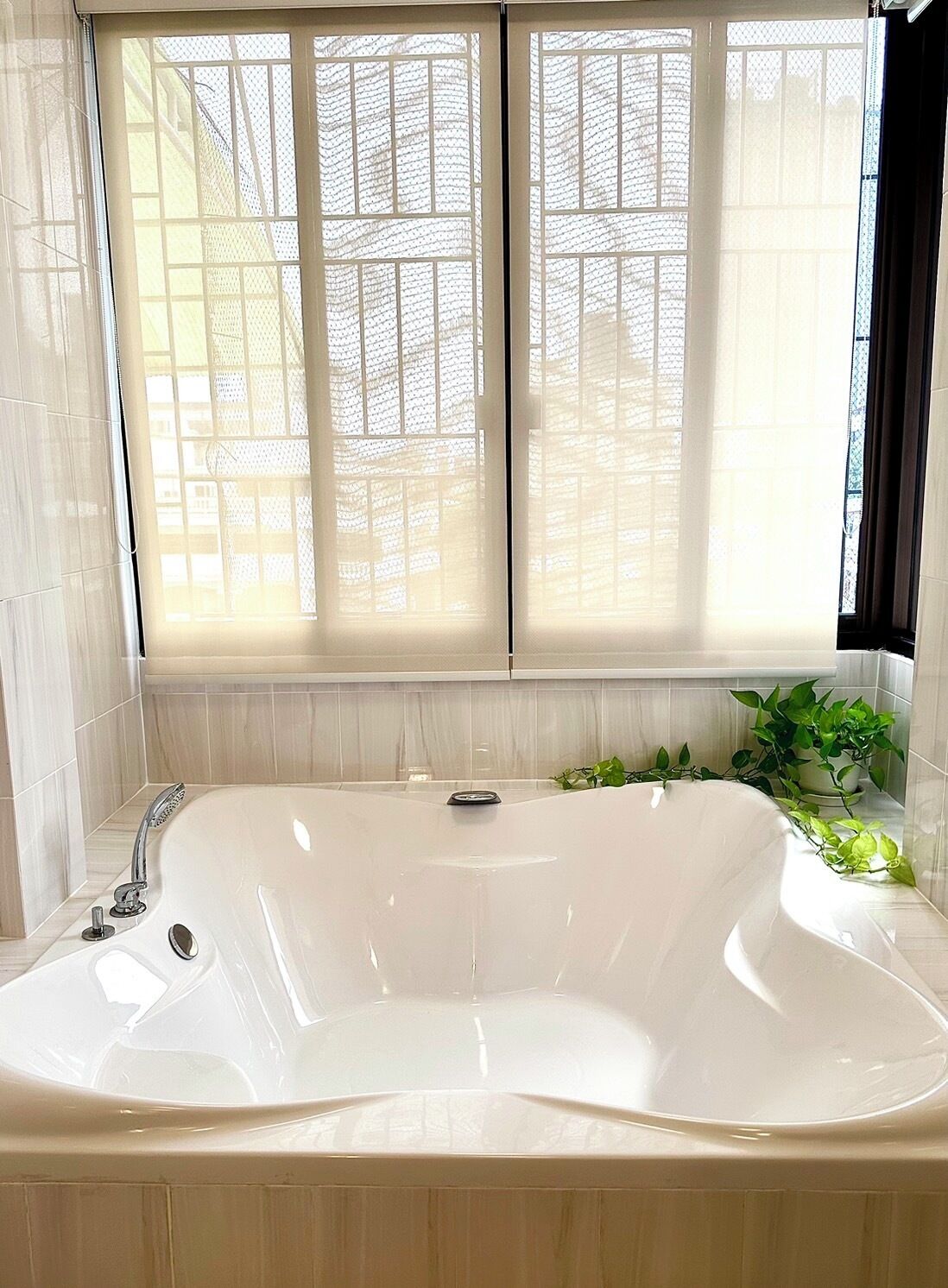 A modern bathroom with a freestanding bathtub, a shower, and a window with a view of a building.