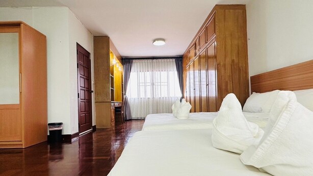 Habitación de hotel con una cama grande, un armario de madera y un escritorio con una silla.