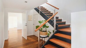 A modern staircase with wooden steps and metal railings, leading to an upper floor.