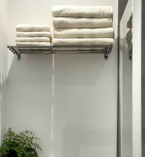A bathroom with a towel rack holding neatly folded towels. - OneFiveSix Unique ApartHotel 2 Bed (Birmingham)