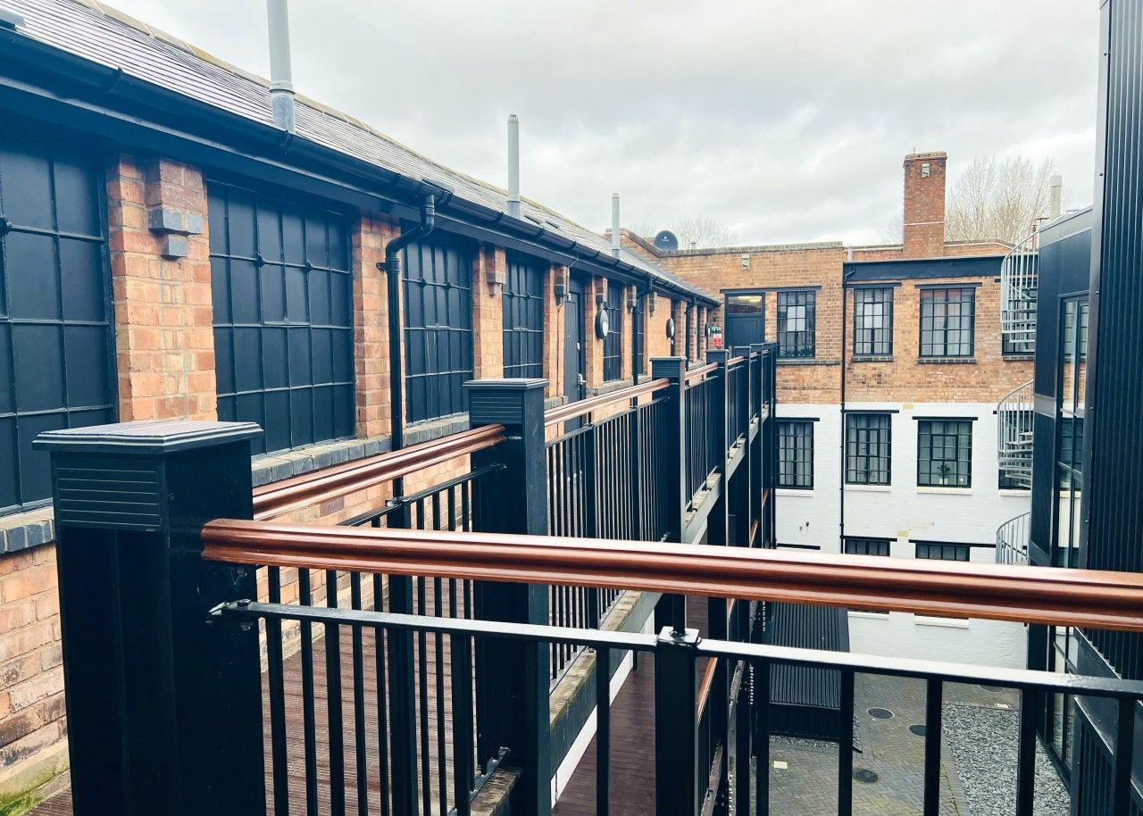 A multi-story building with a brick facade, black railings, and a metal staircase.