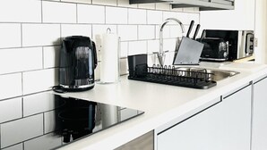 A modern kitchen with white cabinets, a stainless steel sink, and a coffee maker. - OneFiveSix Unique ApartHotel 2-Bed 2-Bathroom (Birmingham)