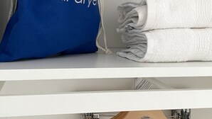 A blue drawstring bag labeled "hair dryer" and two folded white towels on a white shelf. - OneFiveSix Unique ApartHotel 2-Bed 2-Bathroom (Birmingham)