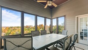 Un espace repas comprenant une table et des chaises, de grandes fenêtres et un ventilateur de plafond.