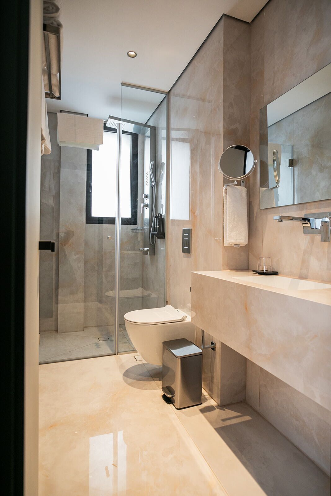 A modern bathroom with a glass-enclosed shower, a toilet, and a vanity with a mirror.