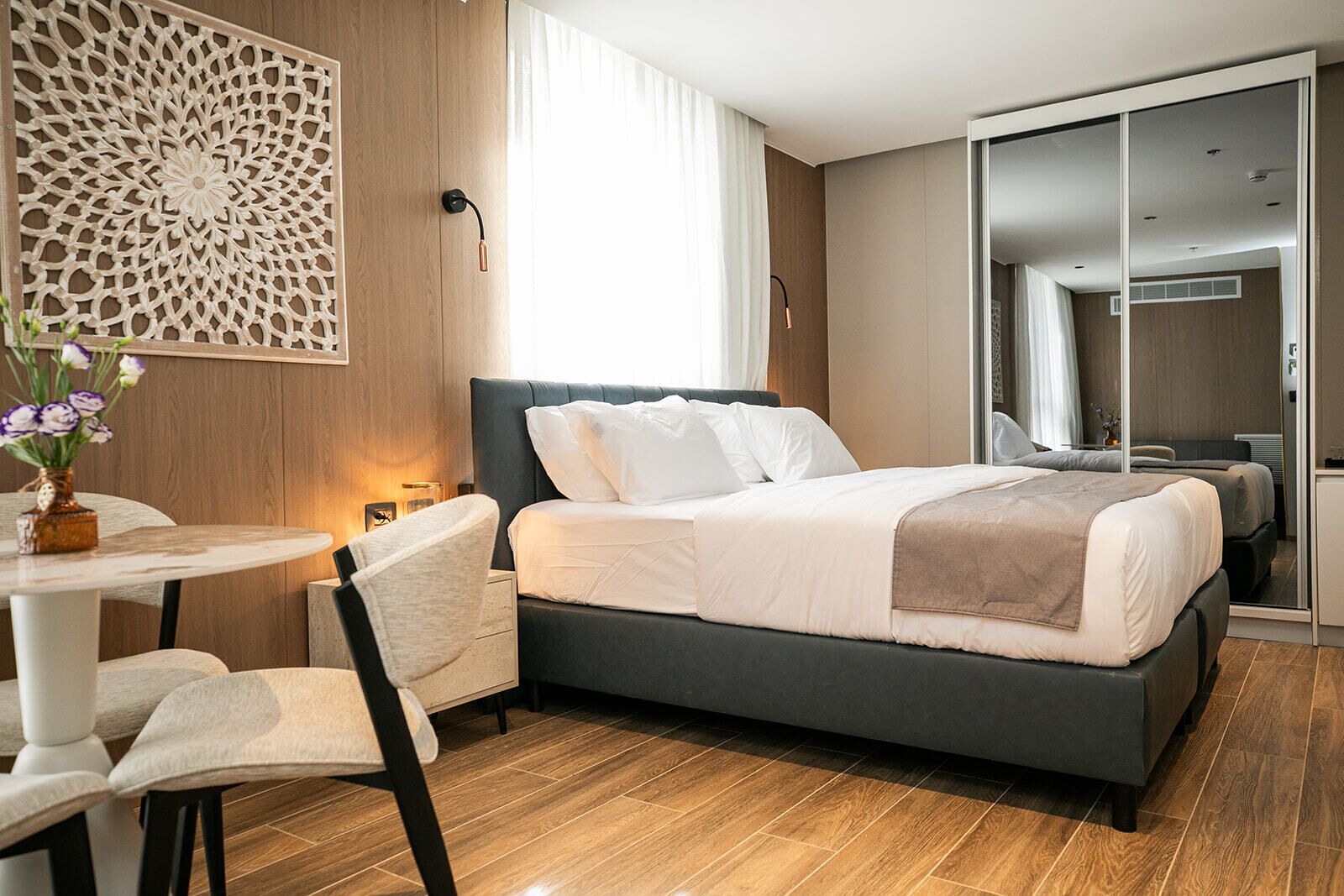 Ein modernes Hotelzimmer mit einem großen Bett, einem Schreibtisch mit Stuhl und einer dekorativen Wandverkleidung.