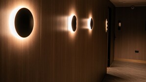 Een gang met houten wanden en ronde lampen.